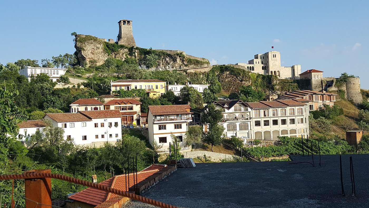 Several houses on a hill with a large historical tower overseeing the village in Kruja, Albania